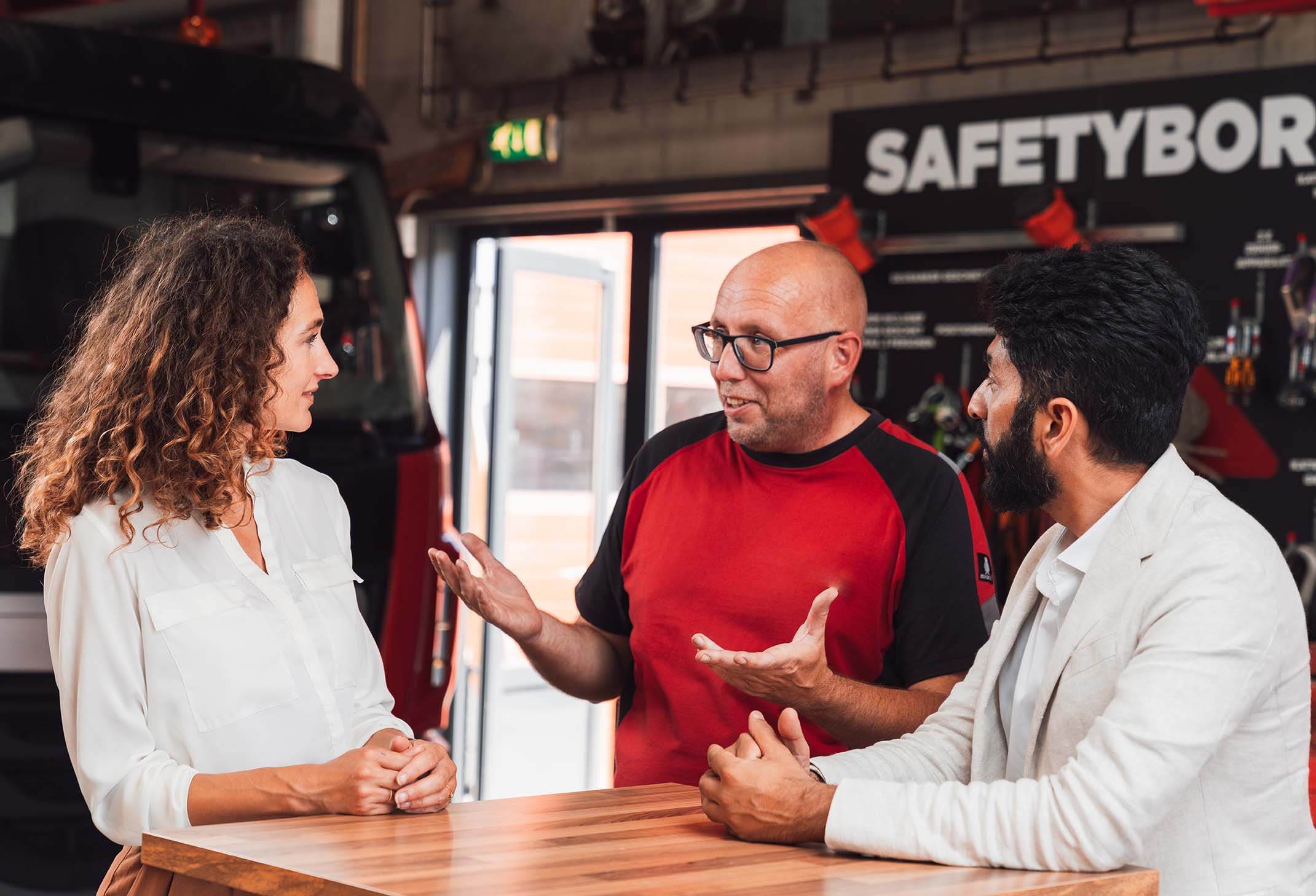 Drie mensen in gesprek op de werkvloer